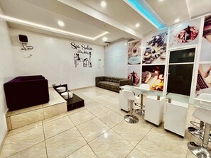 Ein moderner Salon für Wellnessanwendungen mit einem großen Spiegel, einer Couch und einem Glastisch.