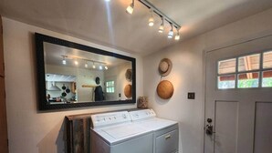 A laundry area with a washing machine, a mirror, and a door.