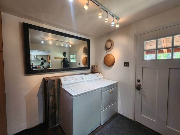 A laundry area with a washing machine, a mirror, and a door.