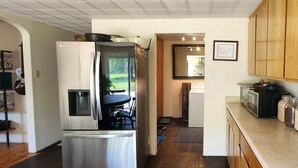 A compact kitchen with a refrigerator, microwave, and stove. There is a dining area with a table and chairs, and a view of the outdoors through a door.