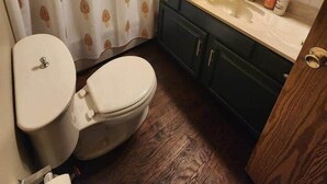 A bathroom with a toilet, sink, and mirror.