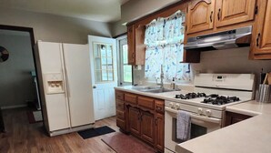 Une cuisine avec des meubles de rangement en bois, un réfrigérateur blanc, une cuisinière et un évier.