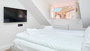 A bedroom with a bed, a TV mounted on the wall, and a window with a view of a building. - 3 TUDISI LUX SUITES by DOMINIUM deluxe double room (loft) (Dubrovnik)