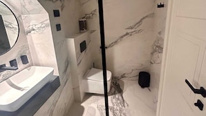 Et badeværelse med et marmorgulv, en hvid vask, et toilet og et badekar.