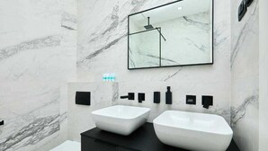 Ein modernes Badezimmer mit zwei weißen Waschbecken, einer schwarzen Ablage, einem Spiegel und einer Toilette.