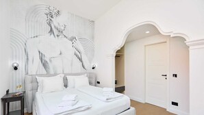 Un dormitorio moderno con una cama grande, un mural de mármol y un arco clásico.