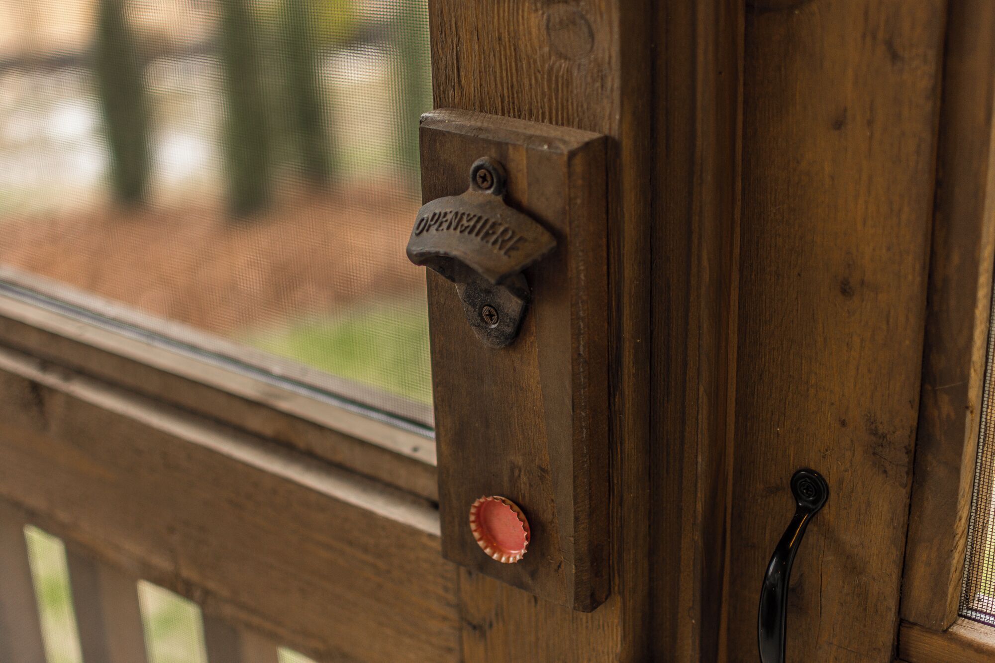 A wooden door with a metal latch and a small, round, red object attached to it.