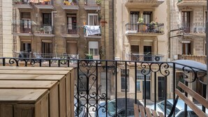 A multi-story building with balconies, some with plants and laundry hanging.