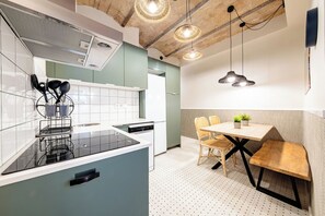 A modern kitchen with a built-in dishwasher, a dining area with a wooden table and chairs, and pendant lighting. - BeBarceloner Badal Apartments - 2 bedrooms (Barcelona)
