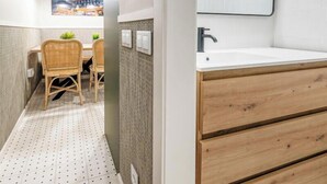 A modern bathroom with a wooden vanity, a large mirror, and a tiled floor.