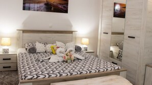 A bedroom with a bed, two bedside tables, a nightstand, a large mirror, and a painting on the wall. - Authentic Dalmatian Treasure Homes - House Stone (Orebic)