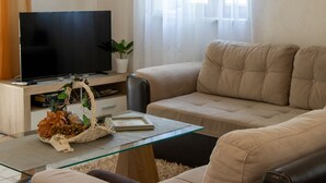 A living room with a flat-screen TV, a beige sofa, a glass coffee table, and a plant. - Authentic Dalmatian Treasure Homes - House Wood (Orebic)