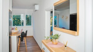Une cuisine moderne avec un plan de travail en bois, un évier et une chaise. Une fenêtre offre une vue sur la verdure à l’extérieur.