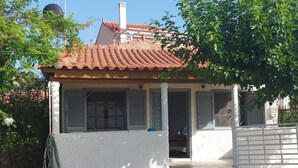 Une maison de plain-pied avec un toit en tuiles, une façade blanche et une porte d’entrée.