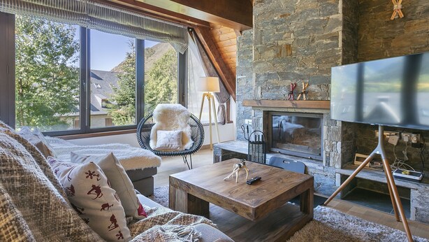 A cozy living room with a stone fireplace, a large window, and a television. - Luderna - Dúplex Sant Marti XII (Gessa)