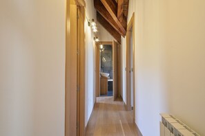Stylish hallway leads to a bathroom with a large sink and separate shower area.