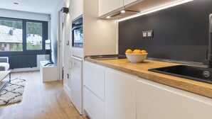 A modern kitchen with white cabinets, a wooden countertop, and a black sink. There is a bowl of lemons on the counter. - Luderna - Apartamento Misharnon (Baqueira)