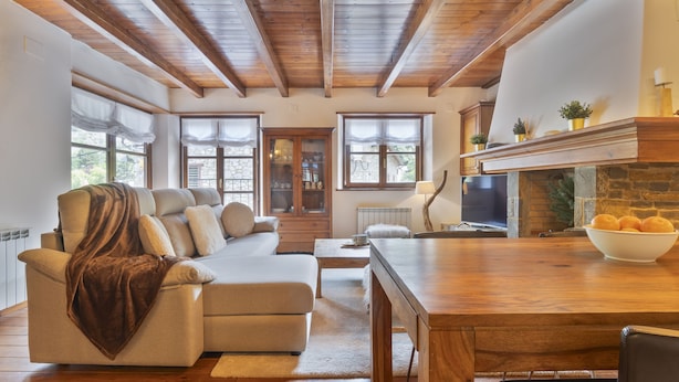 A cozy living room with a sofa, a wooden dining table, and a fireplace. - Luderna - Apto con terraza Rouche (Arties)