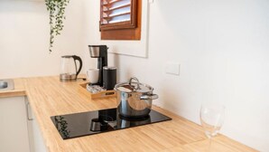 Une cuisine avec un plan de travail en bois, une bouilloire, une machine à café et une casserole sur une plaque de cuisson à induction noire.