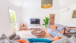 Un salon moderne avec un canapé, une table basse et un téléviseur.