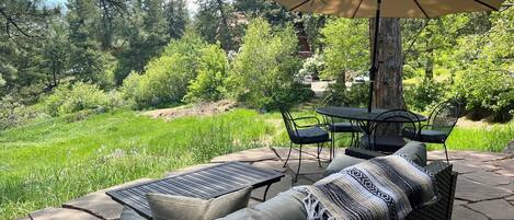 An outdoor patio with a wicker sofa, two chairs, a table, and an umbrella.