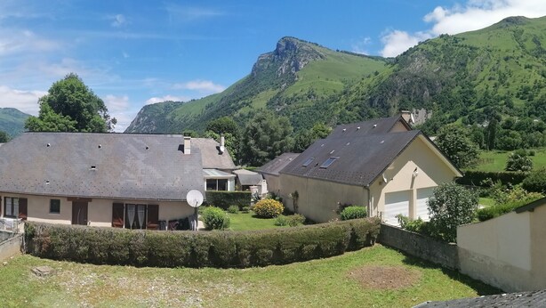 Ein Wohngebiet mit Häusern, einem gepflegten Rasen und einer Bergkulisse im Hintergrund.