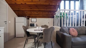 A cozy dining area with a round table, chairs, and a refrigerator. - Rovani 14 - One Bedroom Apartment, Sleeps 3 (Monza)