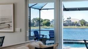 Une chambre avec vue sur un lac, un espace extérieur aménagé avec des chaises et une piscine.