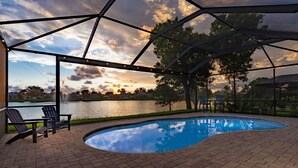 Une piscine avec vue sur un lac et sur le coucher de soleil.