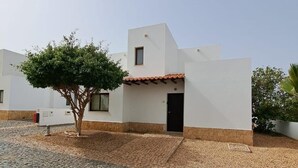 Un edificio moderno con tejado de tejas, una pequeña entrada y un patio de adoquines.