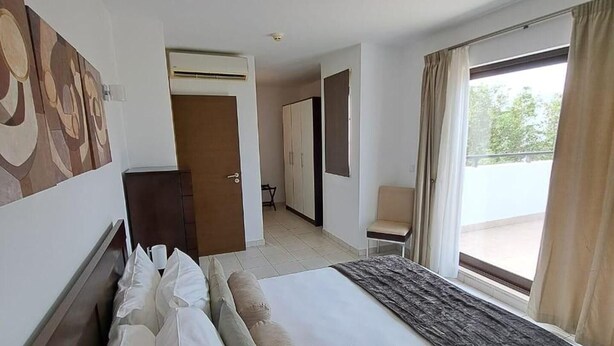 Habitación de hotel con una cama grande, un armario, un escritorio y vistas al exterior.
