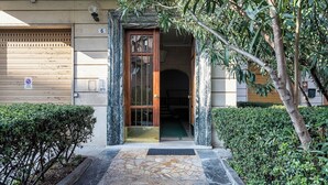 Une entrée d’immeuble avec un chemin en pierre, une porte en bois et une plaque portant le numéro « 6 ».