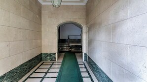 Un couloir doté d’une moquette verte, d’un sol en marbre et d’un escalier menant à un étage supérieur.