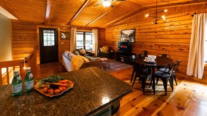 A cozy cabin interior with a wooden interior, a dining area with a table and chairs, a sofa, and a television. - Havenbrook~Rustic luxury, 10acres, hot tub (New Plymouth)