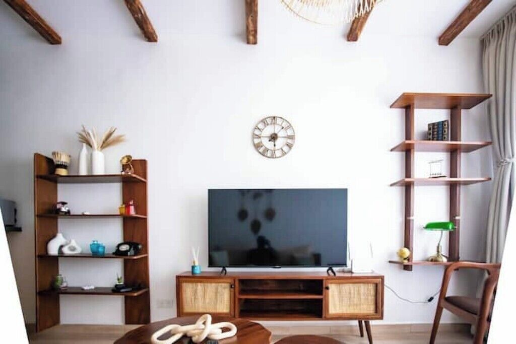Een woonkamer met een televisie, houten planken, een klok en een stoel.