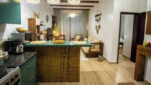 A kitchen with a central island, wooden cabinets, and a dining area with a sofa and chairs. - Rustic Haven Lakeside Condo (Entebbe)