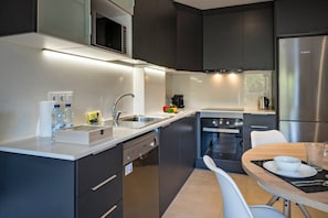 A modern kitchen with a built-in oven, a stainless steel refrigerator, and a dining area with a table and chairs. - Modern Sant Martí Flat Free Jazz 1 (Barcelona)