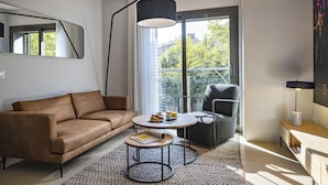 Uma sala de estar moderna com um sofá de couro marrom, uma mesa de centro redonda com uma revista, uma poltrona cinza e um abajur de chão.