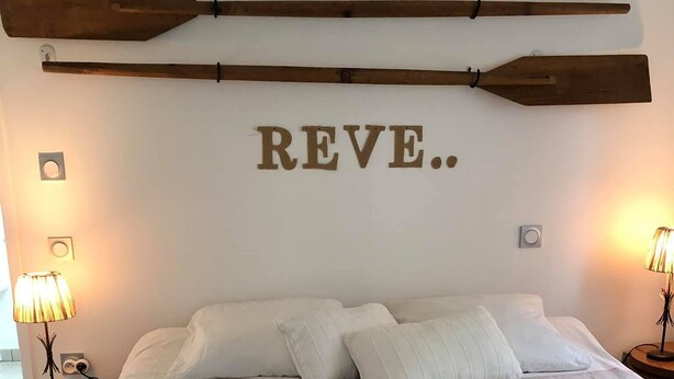 Une chambre à coucher avec un grand lit, deux tables de chevet, une décoration murale en bois et un luminaire fixé au mur.