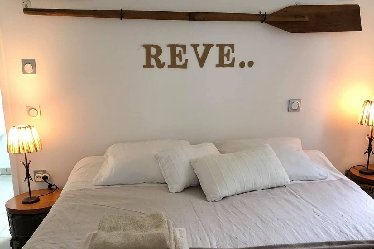 Een slaapkamer met een groot bed, twee nachtkastjes, een houten wanddecoratie en een wandlamp.