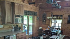 Una cocina de estilo rústico tipo cabaña, con armarios de madera, una isla central e iluminación colgante.