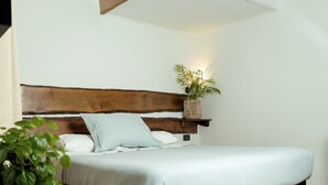 A wooden bed with a white mattress and pillows, a woven basket with a plant on the headboard, and a wooden floor. - Hotel y Restaurant Doña Rode (Andacollo)