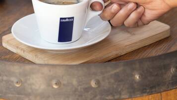 Una taza de café sobre un platito, con una mano apoyada encima.