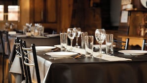 A restaurant table set with plates, cutlery, and glasses, with a dark tablecloth and wooden chairs. - Hotel y Restaurant Doña Rode (Andacollo)