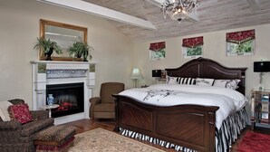 Een slaapkamer met een groot bed, een open haard, een stoel en een nachtkastje.