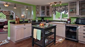 Een keuken met een centraal eiland, lichte kastjes en een groene accentmuur.