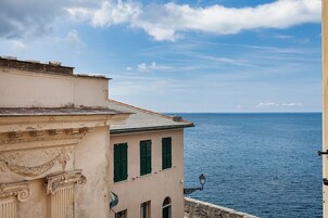 Un edificio costiero con vista sul mare, caratterizzato da elementi architettonici classici e un balcone.