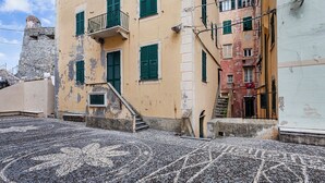 Une rue pavée bordée d’immeubles dotés de balcons et de volets traditionnels.