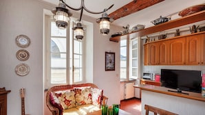 Une cuisine chaleureuse avec des meubles de rangement en bois, une table à manger et un canapé en osier.