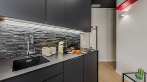 Une cuisine moderne avec un dosseret en pierre, des meubles de couleur sombre et un évier en acier inoxydable.